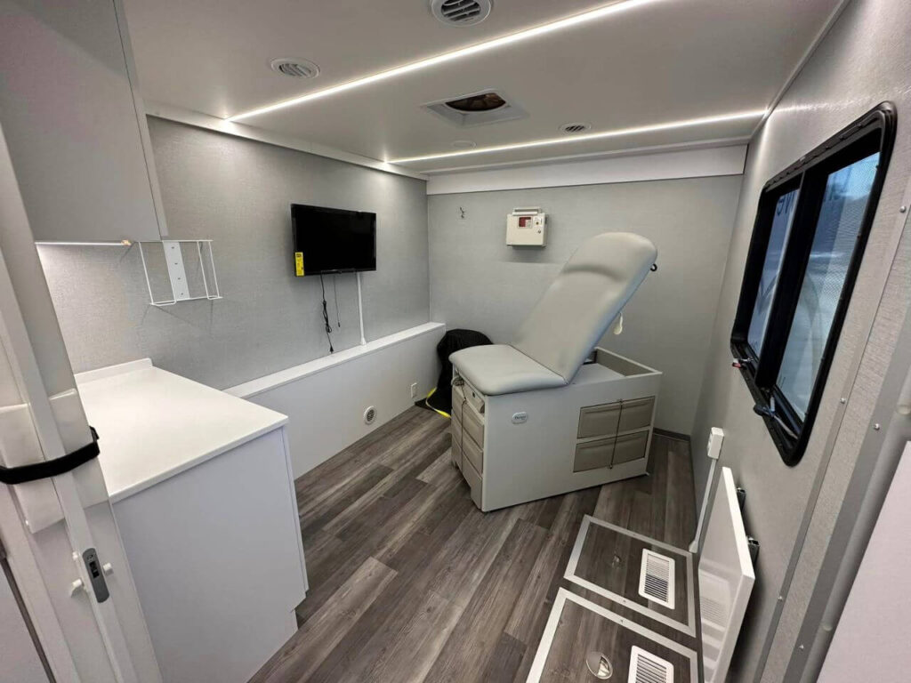 Photo of inside mobile clinic of exam table & room.